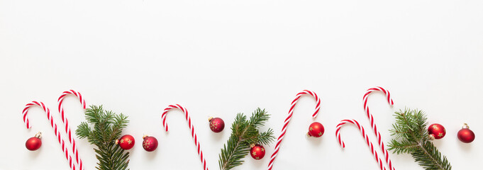Christmas decoration border isolated on white background. Fresh fir twig, red balls and candy canes