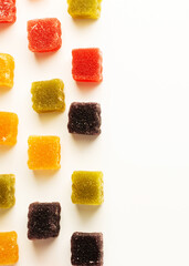 Multi-colored gummies are placed in rows on a white background with space for writing text