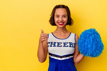 Young cheerleader mixed race woman isolated on yellow background smiling and raising thumb up