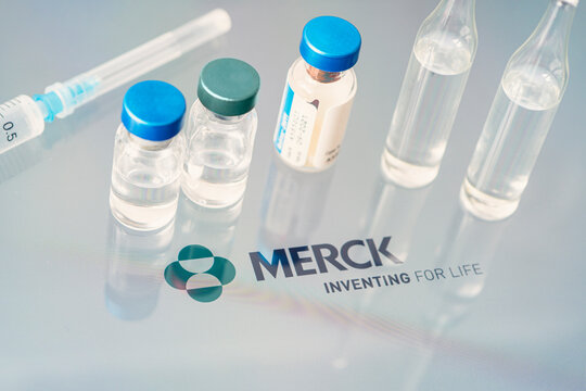 Vials of liquid on a white table and the logo of a large pharmaceutical company.