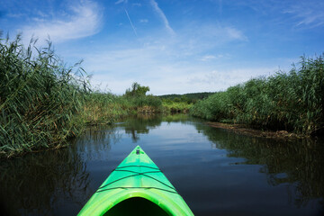 Kayaking on a river. Poland summer on water. Canoe weekend activity. Sunny day river landscape. Rowing boat outdoor. Vacation river travel. Wild narrow river scenery.