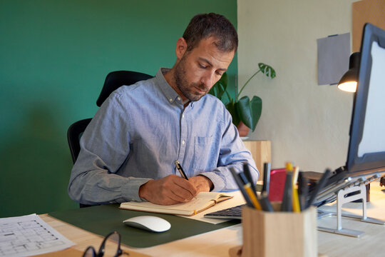 Businessman writing on note pad at home