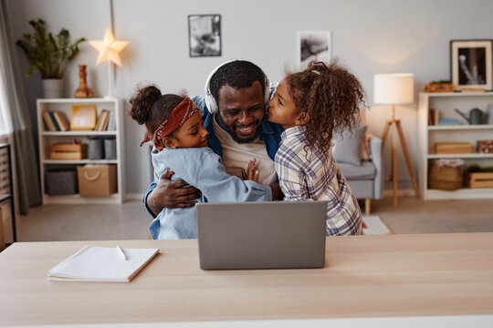 Portrait of two children kissing African-American father working from home, copy space