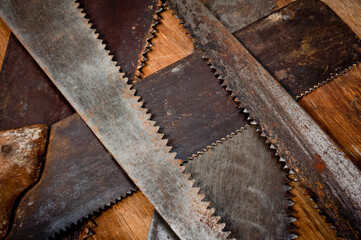 Old vintage metal saws for wood of different shapes and sizes, crumpled on a wooden background.