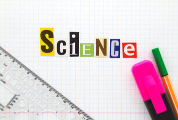 Science - word from cutting magazine clippings on white checkered notebook sheet of paper background with ruler, highlighter and markers pen. Science title concept.