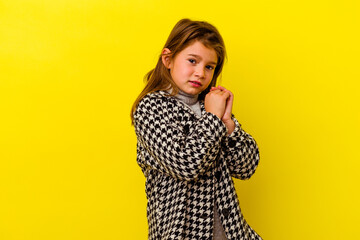 Little caucasian girl isolated on yellow background scared and afraid.