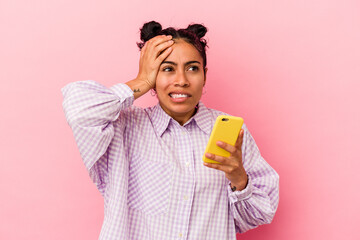 Young latin woman holding a mobile phone isolated on pink background being shocked, she has remembered important meeting.