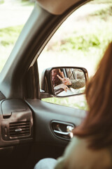 reflection on stunning smiling woman in car rear mirror
