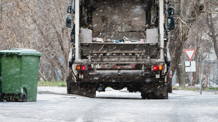 Garbage truck, dustcart with bin lift, household waste removal in residential area in winter,...