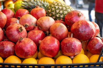 Pomegranate and tropical fruits, bananas, pineapples, lemons, citrus fruits on display at market. Fresh organic  fruits for smoothies, fruit salad, juice