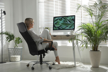 Woman resting on chair near workplace in room. Interior design
