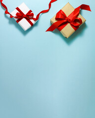 Two white brown paper gift boxes with a red satin ribbon bow and happy birthday sign on top on blue background. Christmas holiday mother and father Valentines days flat lay concept with copy space.
