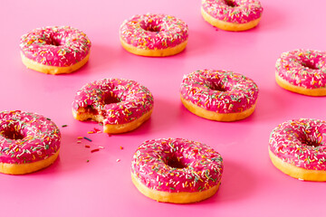 Fototapeta na wymiar Sweet snacks - pink frosted donuts with colorful sprinkles