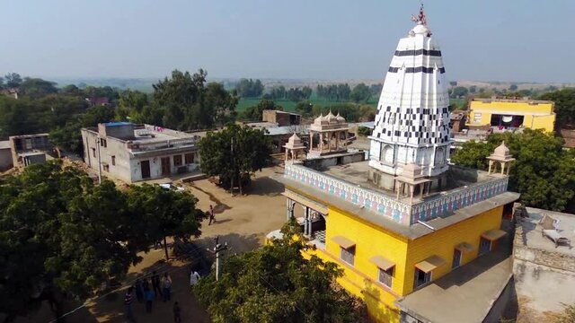 Aerial pedestal up and panning of colorful Hindu temple of rural Indian village of Khera Kiran in Rajasthan, India