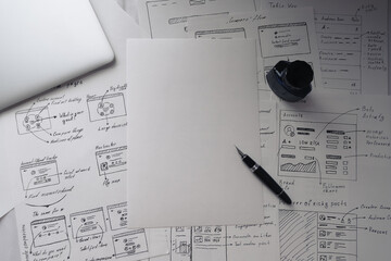 Fountain pen, laptop, ink and blank sheet of paper on background with wireframes of IT project....