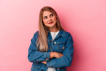 Young russian woman isolated on pink background dreaming of achieving goals and purposes