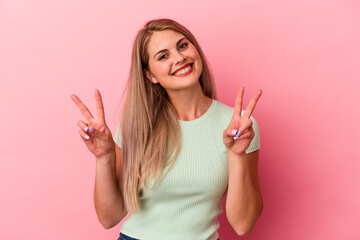 Obraz premium Young russian woman isolated on pink background showing victory sign and smiling broadly.