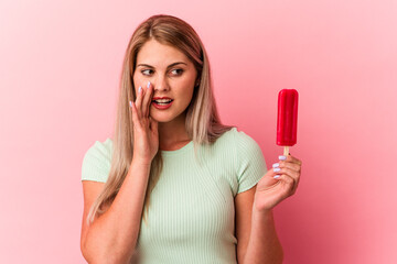 Young russian woman holding an ice cream isolated on pink background is saying a secret hot braking news and looking aside