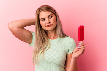 Young russian woman holding an ice cream isolated on pink background touching back of head, thinking and making a choice.