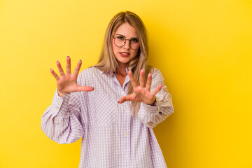 Young russian woman isolated on yellow background upset screaming with tense hands.