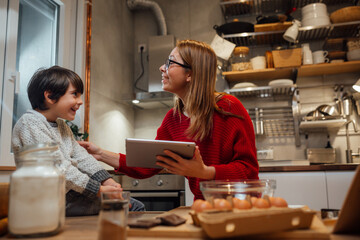 mother and her son looking recipes on digital tablet in kitchen