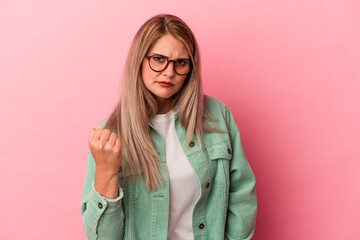 Young russian woman isolated on pink background showing fist to camera, aggressive facial expression.