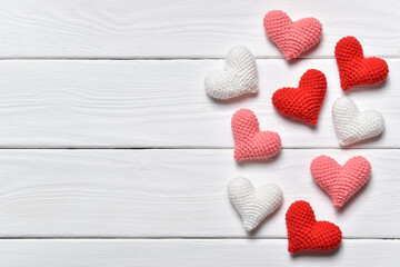 Three colored knitted hearts lie in a heap on a white background.