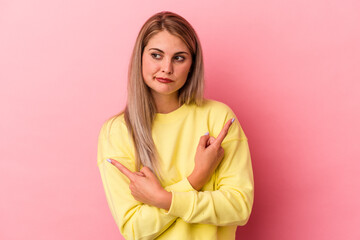 Obraz premium Young russian woman isolated on pink background points sideways, is trying to choose between two options.