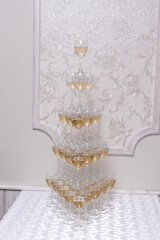 The Champagne Pyramid is a multi-tiered structure of glass goblets filled with champagne, wedding decoration 