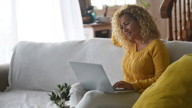 Thoughtful woman sitting on couch using laptop
