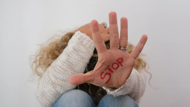 Intimidated woman showing word Stop on her palm