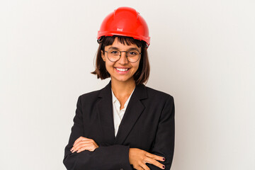 Young architect woman with red helmet isolated on white background who feels confident, crossing arms with determination.