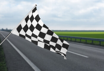 Checkered racing finish flag and asphalt road outdoors