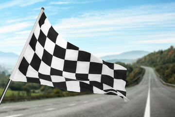 Checkered racing finish flag and asphalt road outdoors