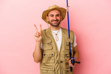 Fototapeta premium Young bald fisherman holding a rod isolated on pink background showing number two with fingers.