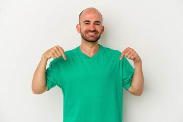 Young bald man isolated on white background points down with fingers, positive feeling.