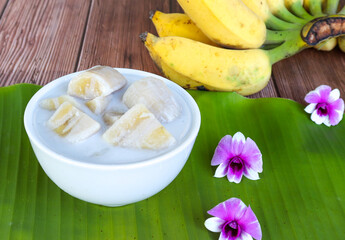 Banana in coconut milk. Fruit dessert. Top view with ripe bananas on white wooden table.