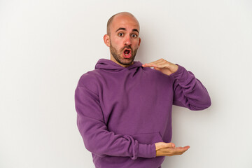 Young bald man isolated on white background holding something with both hands, product presentation.