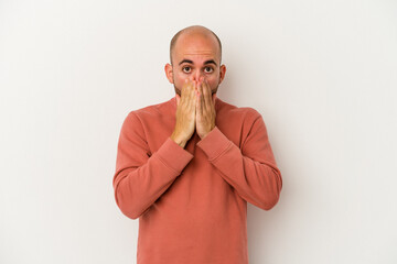 Young bald man isolated on white background shocked, covering mouth with hands, anxious to discover something new.