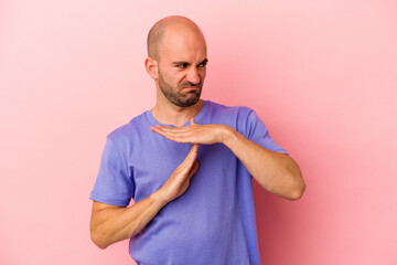 Young caucasian bald man isolated on pink background  showing a timeout gesture.
