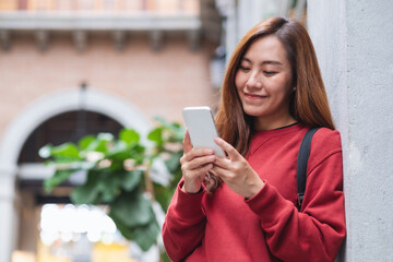 Fototapeta premium A young asian woman holding and using mobile phone while traveling and sightseeing around the city