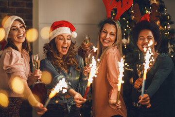 Multiethnic Female Friends Playing With Sparklers And Making Toast As During Christmas Home Party