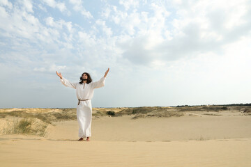 Obraz premium Jesus Christ raising hands in desert. Space for text