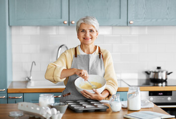 cooking food, people and culinary concept - happy smiling woman making dough or batter on kitchen at home