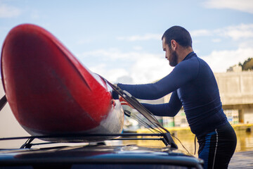 Young boy tying his kayak on top of the car hood to transport