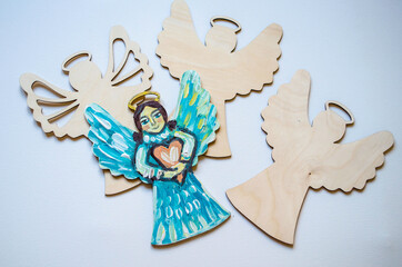 Christmas angels with handmade acrylic painted heart on white background.