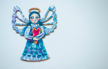 Christmas angel with handmade heart painted with acrylic g on a white background. Holiday template.