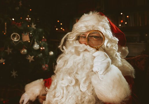 Santa Claus inside a home, portrait with a magnifying glass 