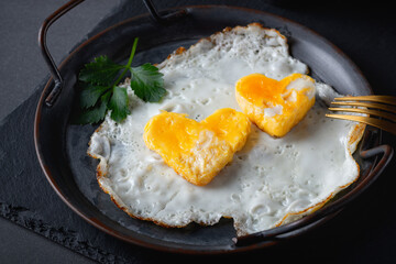 Homemade fried egg in a vintage pan a grey background. Heart-shaped yolk.View from above