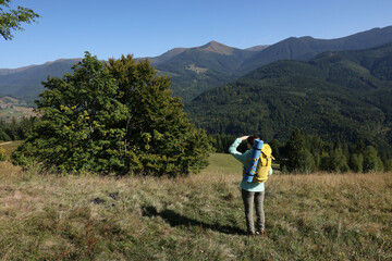 Obraz premium Tourist with backpack enjoying view in mountains on sunny day